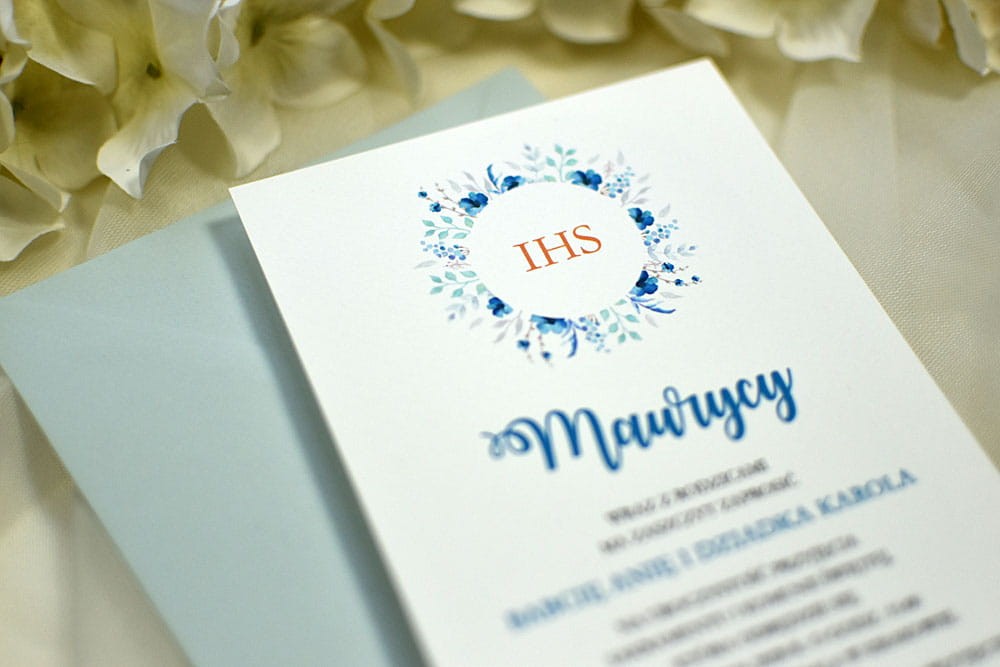 Zaproszenie na Chrzest lub Komunię Świętą z niebieskim wiankiem z kwiatów i napisem IHS.
